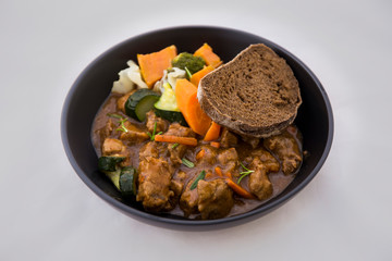 beef casserole in the bowl with steamed vegetable