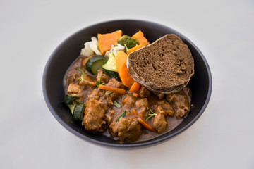 beef casserole in the bowl with steamed vegetable