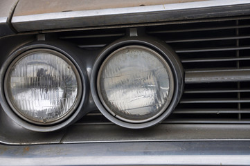 Close up of one side of double round headlights on an old classic car