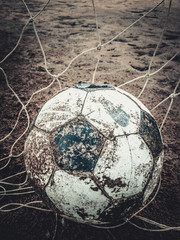 Dirty football old on the ground field after rain.