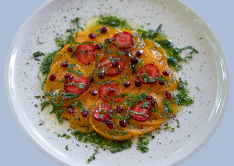 Sprinkle a dish of yellow tomatoes and fresh strawberries with herbs. Food on a white plate. A...