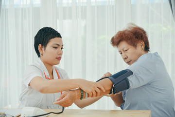 Asian doctor checking up her patient old woman in office.