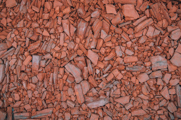 Background in grunge style from the shards of old broken red bricks. Fragments of small pieces. The view from the top. The surface of the table for shooting flat lay. Copy space