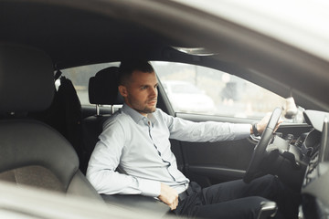 Conversations and phone calls, negotiations. Portrait of a young successful man in the car.