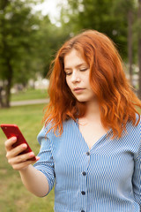 Beautiful red-haired girl with a mobile phone. mobile communication, mobile phone. Telephone conversation.