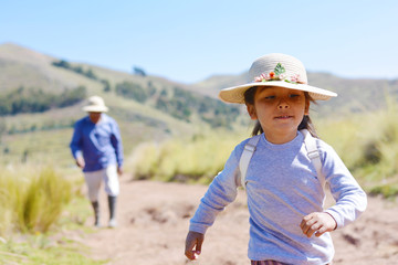Little latin girl with backpack running in the countryside.