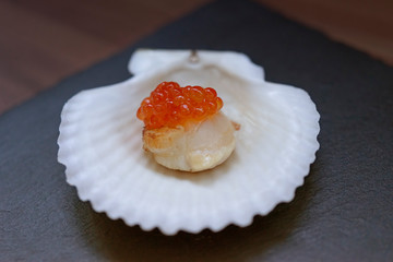 Red caviar on a scallop fillet and on a white shell