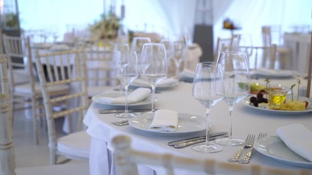 Glasses, plates, Cutlery and napkins. Decorated tables with flowers for the party. Wedding reception, birthday, anniversary