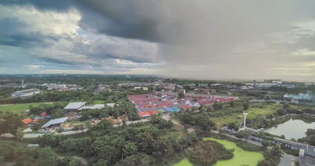 Obraz premium Aerial view evening above village and green rice paddy fields with heavy raining in dark sky background, Krajub reservoir, Ban Pong, Ratchaburi, Thailand.