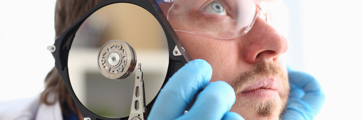 Repairman attached the hard drive of the computer to his ear