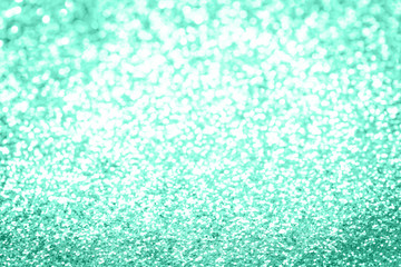 Trendy monochrome bokeh lights background in shades of pastel green color. Festive confetti glitter backdrop