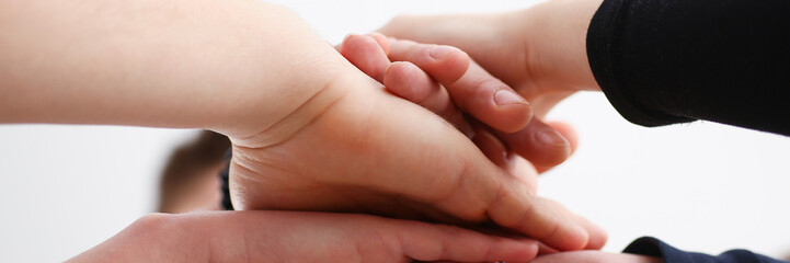 Group of people in suits crossed hands in pile for win