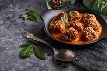 homemade meatballs with tomato sauce and spinach in a plate on a dark background