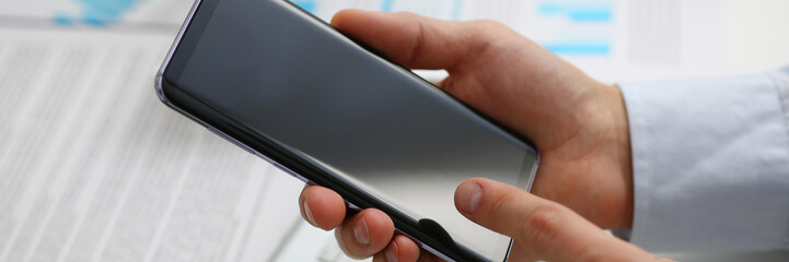 A businessman holds a new smartphone in his hand