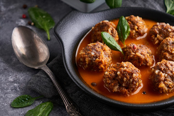 Tasty homemade meatballs with tomato sauce and spinach in a plate on a dark background Copy space