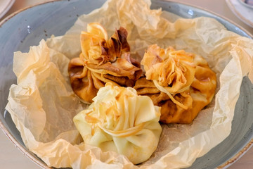 Julienne baked in dough served on a plate on baker paper with tea and butter. Close-up view