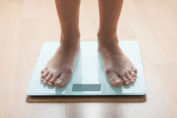 Healthy diet, fitness and weight loss concept. The legs of a young woman on the scales. Checking the weight.