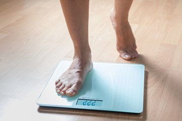 Healthy diet, fitness and weight loss concept. The legs of a young woman on the scales. Checking the weight.