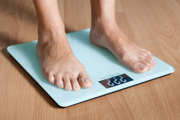 Healthy diet, fitness and weight loss concept. The legs of a young woman on the scales. Checking the weight.