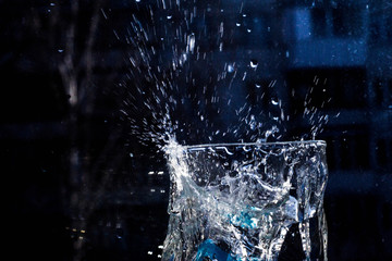 The water in the glass splashes in different directions. A glass with a crooked distorted glass...