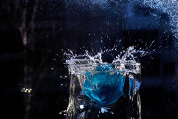 The water in the glass splashes in different directions. A glass with a crooked distorted glass...