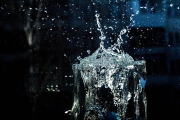 The water in the glass splashes in different directions. A glass with a crooked distorted glass...