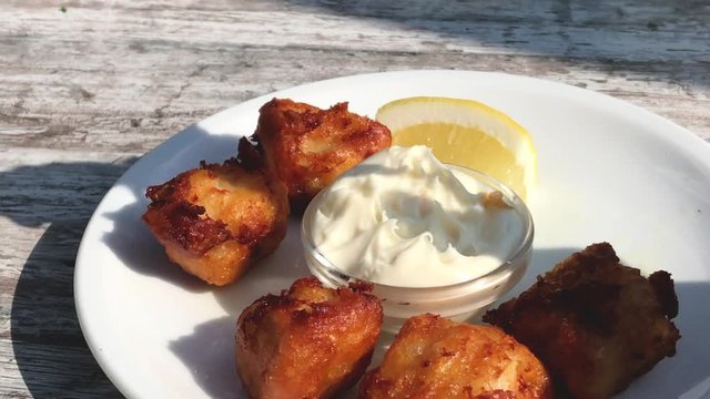 Eating fried cod with sauce and lemon outdoors in a beer garden Traditional German food Kibbeling