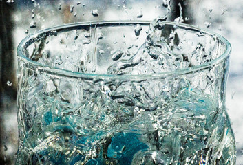 The water in the glass splashes in different directions. A glass with a crooked distorted glass...