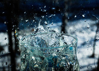The water in the glass splashes in different directions. A glass with a crooked distorted glass...