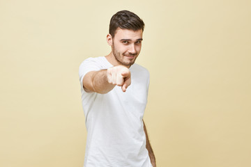 Picture of attractive self confident young brunette male in white casual t-shirt looking straight...