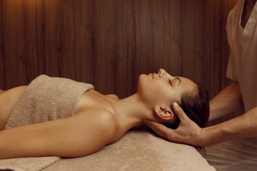 Male masseur rubbing neck vertebrae to young woman