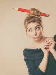 Obraz premium Thinking blonde woman having big pencil in hair