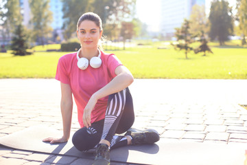 Beautiful young woman looking away while sitting on exercise mat at park, relaxing after training.