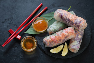 Traditional vietnamese spring rolls with vegetable filling and dipping sauces, high angle view over...