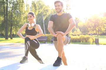 Happy young couple exercising together in a park.
