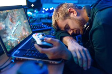Male gamer sleeping at his laptop after challenge