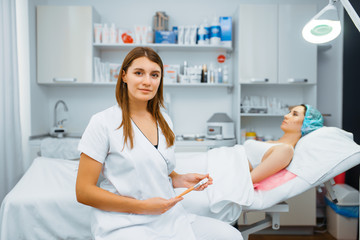 Cosmetician near female patient on treatment table