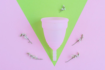 pink menstrual Cup on pink and green background. woman period concept.