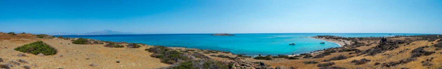 amazing panorama from a desert to a nice gulf , beach , rocks and deep azure sea and high mountains and blue sky on the background. Greek landscape.