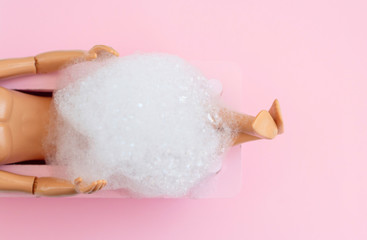 doll man legs in pink bath on pink pastel background. creative minimalistic concept of relax. top view. 