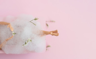 doll legs in pink bath on pink pastel background. creative minimalistic concept of relax. top view. 