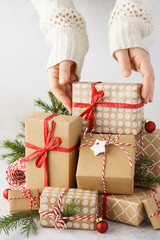 Young woman hands taking a gift box from a big stack of gifts.