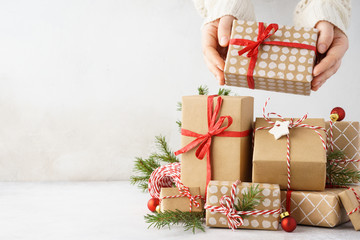 Young woman hands taking a gift box from a big stack of gifts.