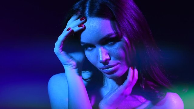 Colorful portrait of beauty sexy model girl. Beautiful seductive woman posing. Gorgeous Brunette girl in neon light. Beauty Glamour sensual lady with long curly hair posing in vivid lights 4K Slowmo