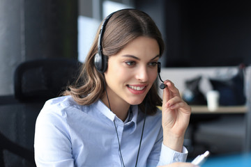 Woman customer support operator with headset and smiling.