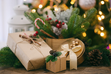 Christmas decoration sweet background with gift box, pine leaves and pine cones, white lantern and candy cane on wood table with copy space. Bokeh Christmas tree wallpaper for xmas celebration