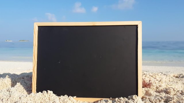 A blank black chalkboard on the soft white sand of tropical beach in the Caribbean