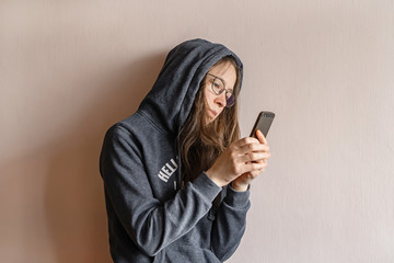 Brunette woman with long hair with smartphone in hand on light background. 