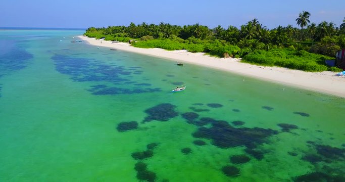 fishing boat approaching tropical island with palms and beautiful white sand beach