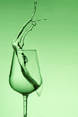 beautiful splashes of water in a wine glass, with green filter, close up with copy space.